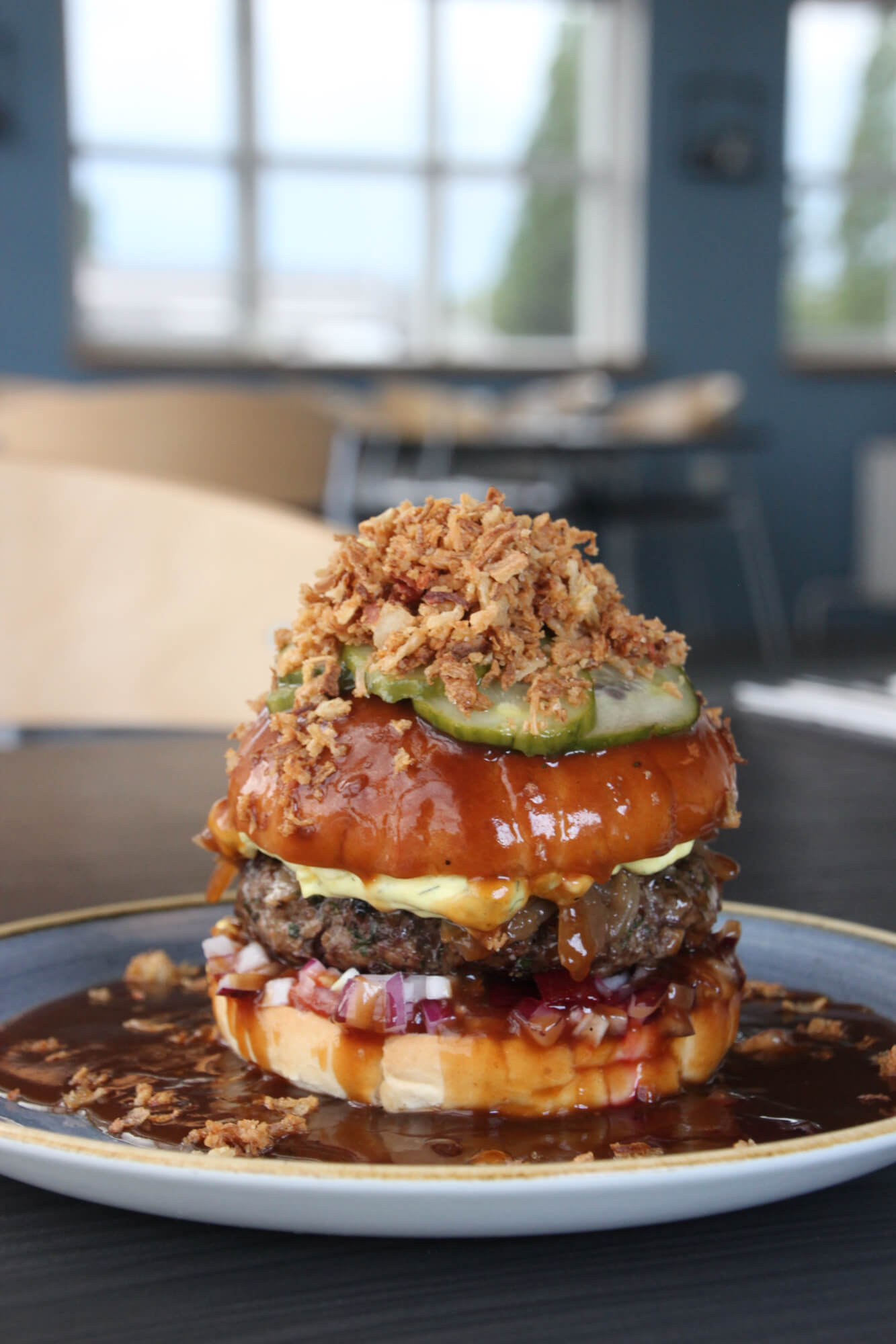 Husets burger med sprøde løg, pickles og tomat
