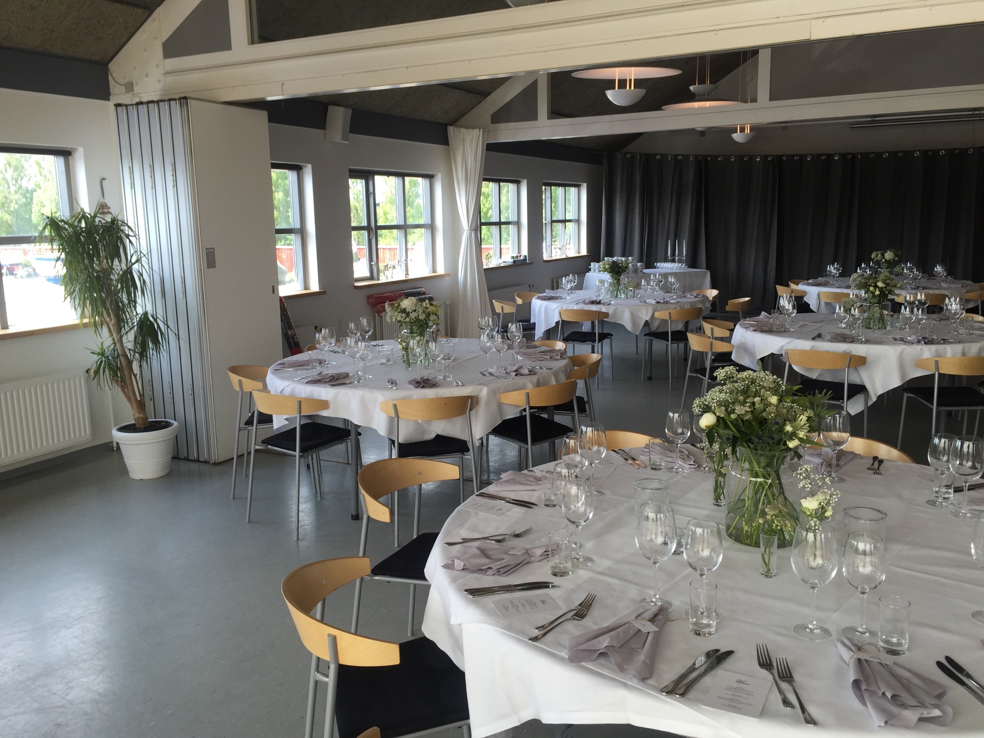 Selskabslokale med runde borde og friske blomster