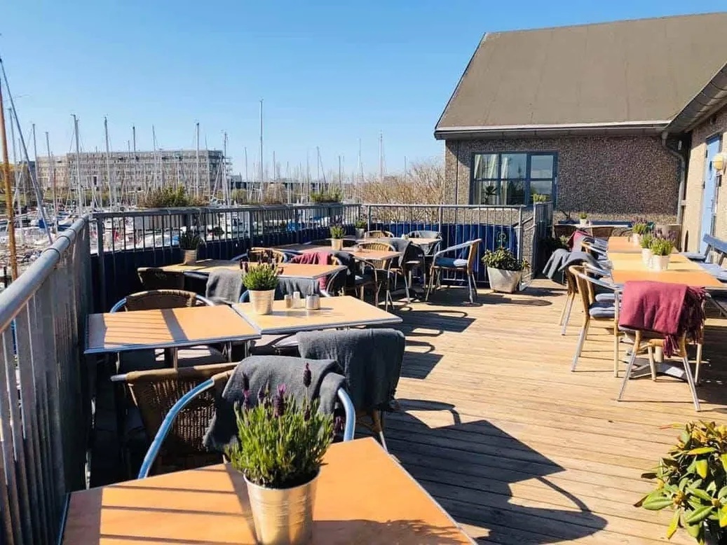 Solfyldt terrasse ved marinaen med opdækkede borde